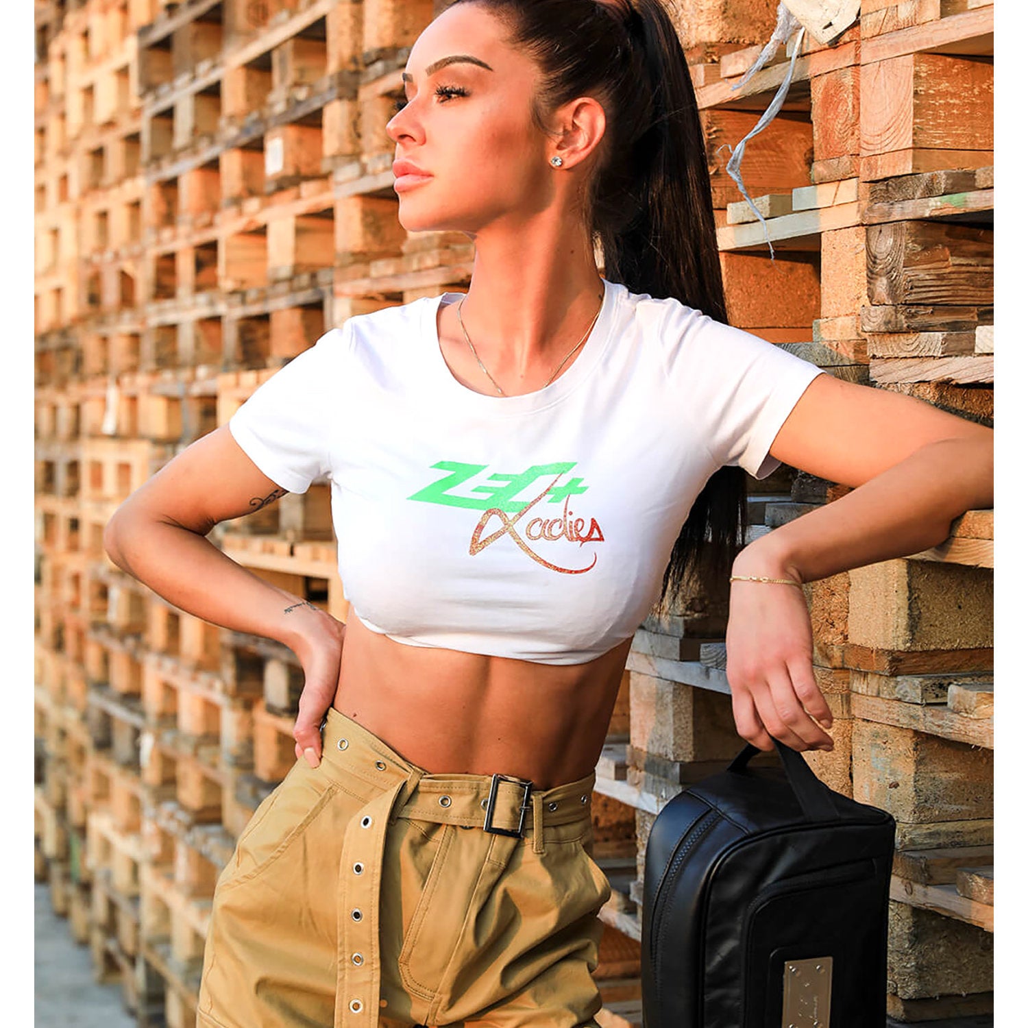 Zecplus Lifestyle Kulturbeutel Schwarz Frau vor Paletten Holzlager trägt den Kulturbeutel